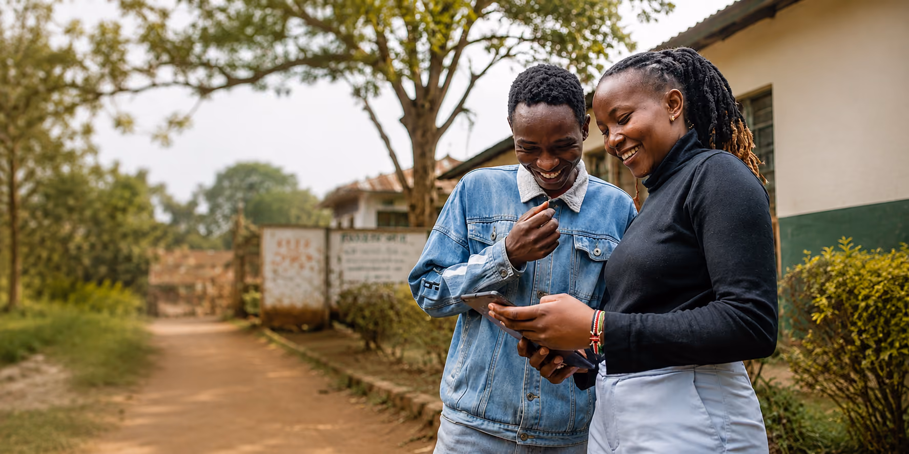 Two young people reviewing information together on a phone in a community setting.
